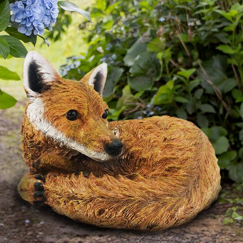 Curled fox garden ornament placed among plants outdoor woodland decoration